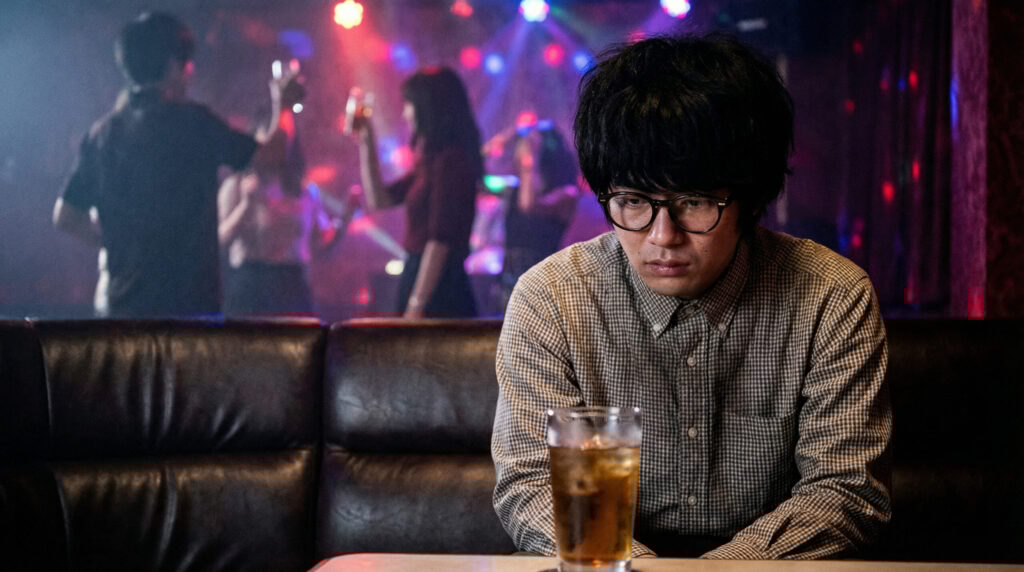 ポツンと座ってグラスの水滴を眺めている男性